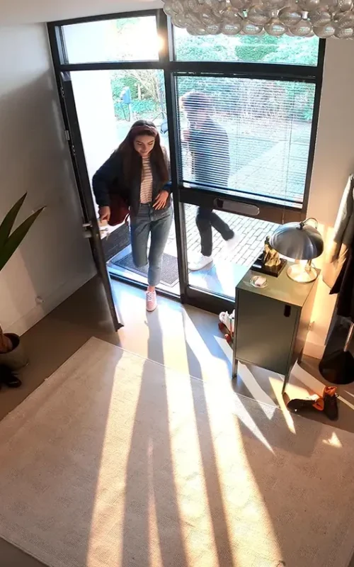Femme filmée par une caméra de vidéosurveillance entrant dans une maison