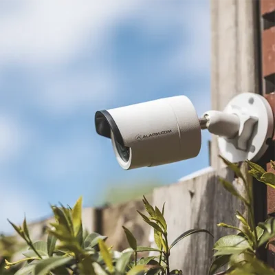 Caméra de surveillance sur un mur au dessus d'une barrière en bois