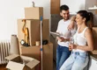 Couple au milieu des cartons de déménagement avec une tablette en main