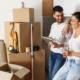 Couple au milieu des cartons de déménagement avec une tablette en main