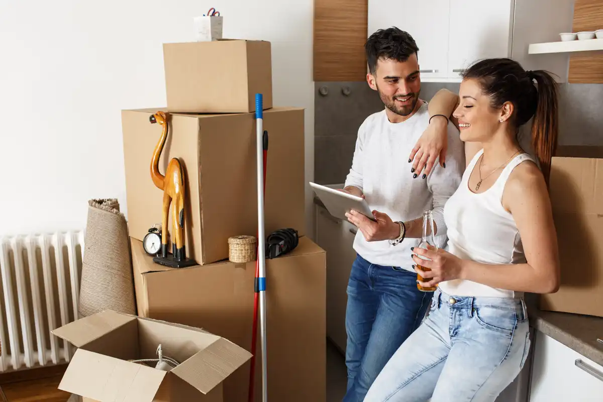 Couple au milieu des cartons de déménagement avec une tablette en main