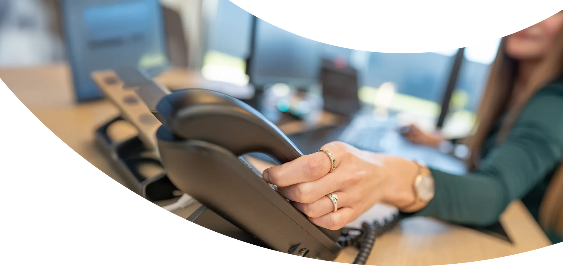 Plan rapproché de la main d'une conseillère décrochant le téléphone fixe