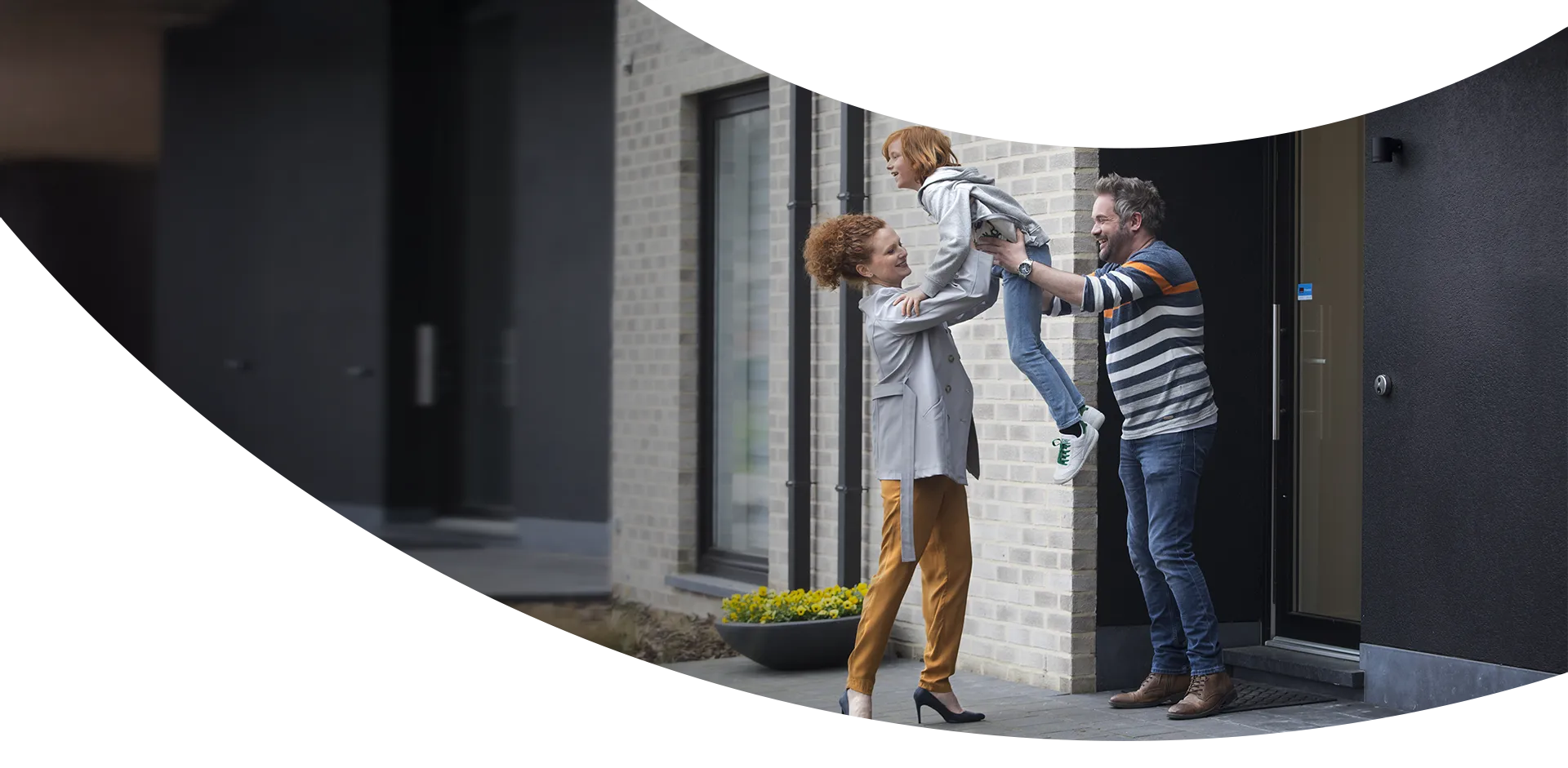 Couple heureux sur le pas de la porte se passant un enfant de bras en bras